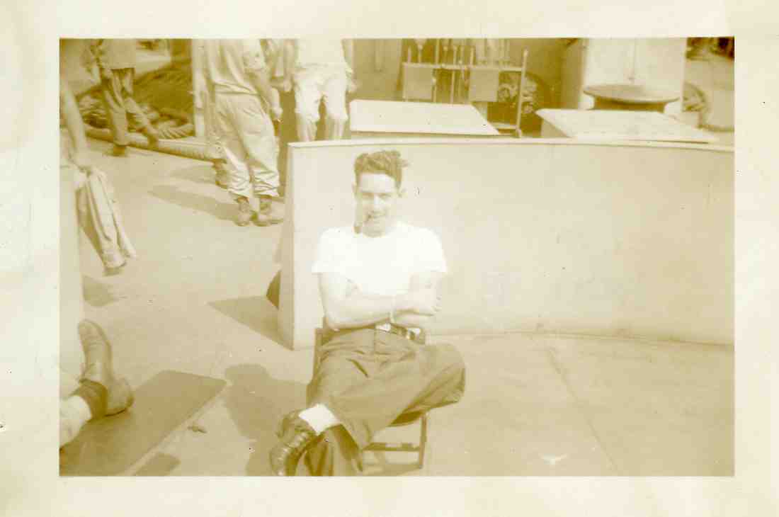 Roy Hixson sitting in a chair on a ship deck, leg crossed